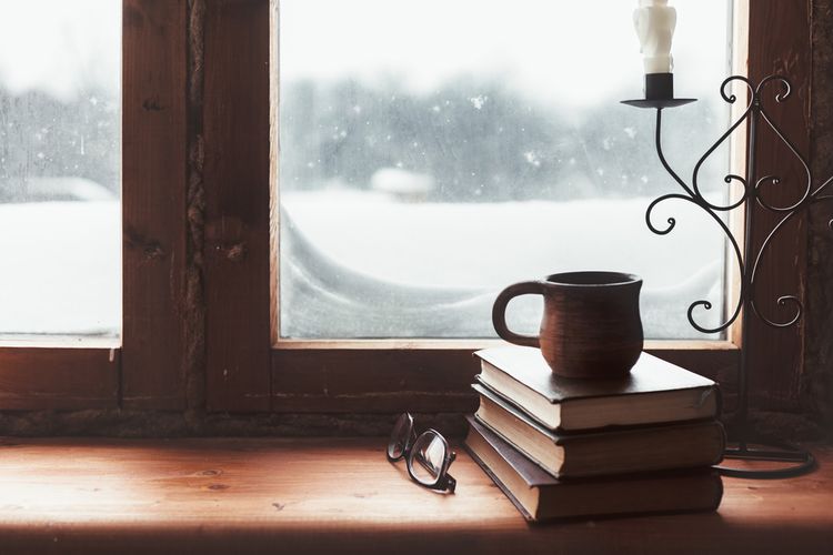 snow weather outside a window with books in foreground, keep your home warm