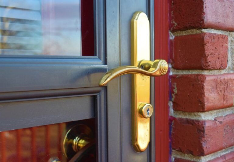Image is of a gold brass handle of a storm door