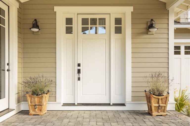 Image is of a white fiberglass exterior door with small windows and porch scene around it
