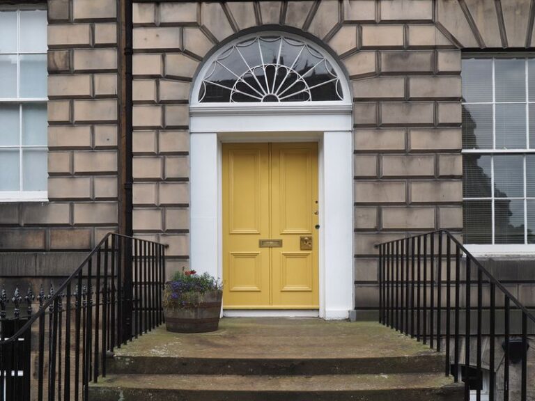 Image is of a yellow entry door with a transom window above it.