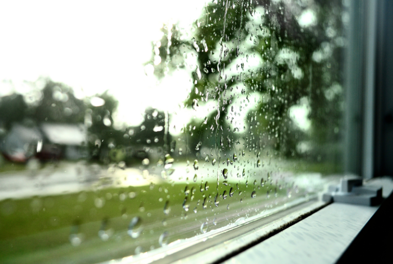 Image is of a view from an interior of a home of a rainy window, concept of window damage after hurricane Helene