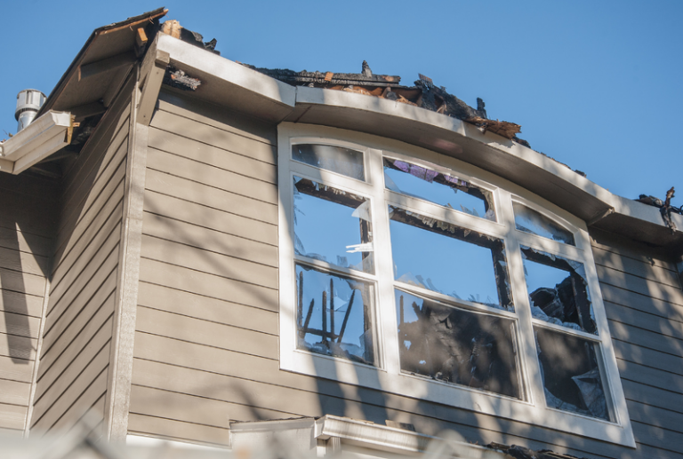 Image is of a broken window and roof from a storm, concept of the window damage insurance claims