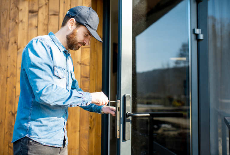 Image is of a man fixing an exterior door handle, concept of common door problems and how to fix them